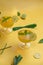 Herbal green tea with lemongrass in glass cup with fresh limes. Top view of two cups of Lemon Grass Drink on a Yellow Background