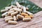 Herbal Medicines - Natural herb capsules on green leaf and rustic background , selective focus