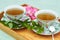 Herbal mint tea served in two china porcelain cups with bunch of fresh leaves nearby