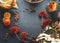 Herbal tea background frame with rowan berries, orange slices , glass teapot and cup on dark rustic background. Top view