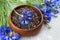 Herbal tea blend with dried cornflower petals in wooden bowl with fresh cornflowers