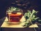 Herbal tea made from sage in glass cup standing on books, nearby lies a bundle of sage over dark wooden background