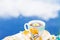 Herbal tea in teacup decorated with flowers outdoors in background of blue sky with clouds