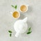 Herbal tea with two white tea cups and teapot, with green tea leaves. Flat lay, top view. Tea concept