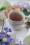 Herbal tea with wisteria, irises, white callas on gray background.