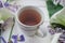 Herbal tea with wisteria, irises, white callas on gray background.