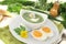 Herbs soup with eggs, a dollop of cream