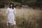 Herbs and wildflowers in field blurred image of stylish girl in linen dress and hat posing. Boho woman relaxing in countryside,