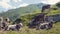 A herd of Alpine cows resting on the green hills of Alps, high mountains and large stones on the background. Farming