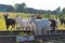 A herd of domestic woolen and dairy goats grazes near the railway in the village on a bright summer sunny day against the backdrop