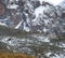 Herd of mountain sheep is masked against the background of rocks, stones and snow