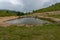 a herd of sheep and donkeys standing around a drying lake drinking water in the mountains in Romania in Muntia Ciucas