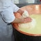 herdsman Cheesemaker collects cheese from the copper cauldron w