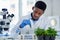 Here goes nothing. a focused young male scientist placing tiny plants into vials ready to be experimented on inside of a