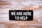 We Are Here To Help. Chalk board hung on a wooden wall