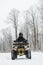 Hero shot of a man on a quad bike in winter background. Portrait of a quadricycle rider in snowy forest