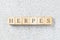 Herpes word written on building blocks on grey