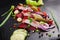 Herring appetizer with beets and gherkin on black slate board