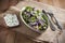 Herring fillet slices under red onions and chives and a sandwich with rye bread and curd, dill and chives. Knife and fork. Burlap