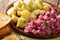 Herring salad with beets, onions, apples, pickled with a side dish of boiled potatoes close-up in a plate. horizontal