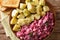 Herring salad with beets, onions, apples, pickled with a side dish of boiled potatoes close-up in a plate. Horizontal top view