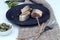 Herring slices on a black plate with forks and napkin, side view, close-up