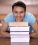 Hes eager to learn. Portrait of a young man sitting down and resting his head on some textbooks.