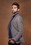 Hes a snappy dresser. a stylishly dressed young man posing against a brown background.