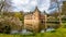 Het Oude Loo castle with its bridge, surrounded by its moat with reflection in the water and trees