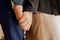 Heterosexual couple without faces holding hands close-up, on the womans hand engagement and wedding ring made of silver metal,