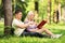 Heterosexual couple seated on a grass and reading a novel in a p