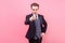 Hey you! Portrait of irritated bossy young businessman in tuxedo pointing at camera. studio shot isolated on pink background