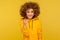 Hey you! Portrait of positive curly-haired young woman in urban style hoodie pointing to camera, showing direction