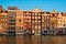 Hhouses and tourist boats on Amsterdam canal pier Damrak on sunset