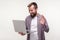 Hi! Portrait of positive bearded man waving hand at laptop, making video call, online talking on social network. white background