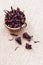 Hibiscus Roselle, karkade dry flowers in wooden bowl on burlap background with copyspace close-up.