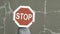 Hidden person carries big stop road sign from left to right. Bold red against cracked gray wall