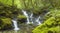 A hidden village waterfall surrounded by moss-covered rocks.