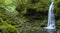 A hidden village waterfall surrounded by moss-covered rocks