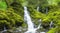 A hidden village waterfall surrounded by moss-covered rocks.