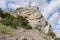 High acute cliff covered with trees on the blue sky background