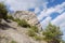 High acute cliff covered with trees on the blue sky background