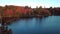 High aerial flying backward over the lake surrounded by colorful trees