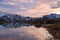 High altitude alpine lake in idyllic landscape. Reflection of snowcapped mountain range and scenic colorful sky at sunset. Wide an