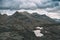 High altitude rocky landscape and little lake. Majestic alpine landscape with dramatic stormy sky. Wide angle view from above, ton