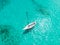 High angle aerial drone bird`s eye view of a sailing yacht with sails lowered anchored in shallow, turquoise water