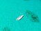 High angle aerial drone bird`s eye view of a sailing yacht with sails lowered anchored in shallow, turquoise water