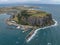 High angle aerial drone view of landmark the Nut, an extinct volcano table mountain, the harbour and the town of Stanley