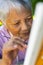 High angle close-up of serious biracial senior woman painting with paintbrush on canvas in yard