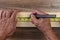 High angle closeup of a carpenters hands using a tape measure to mark a cut line on a board